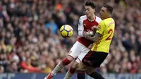Gelandang Arsenal, Mesut Ozil, berebut bola dengan bek Watford, Jose Holebas, pada laga Preimer League di Stadion Emirates, Minggu (11/3/2018). Arsenal menang 3-0 atas Watford. (AP/Matt Dunham)