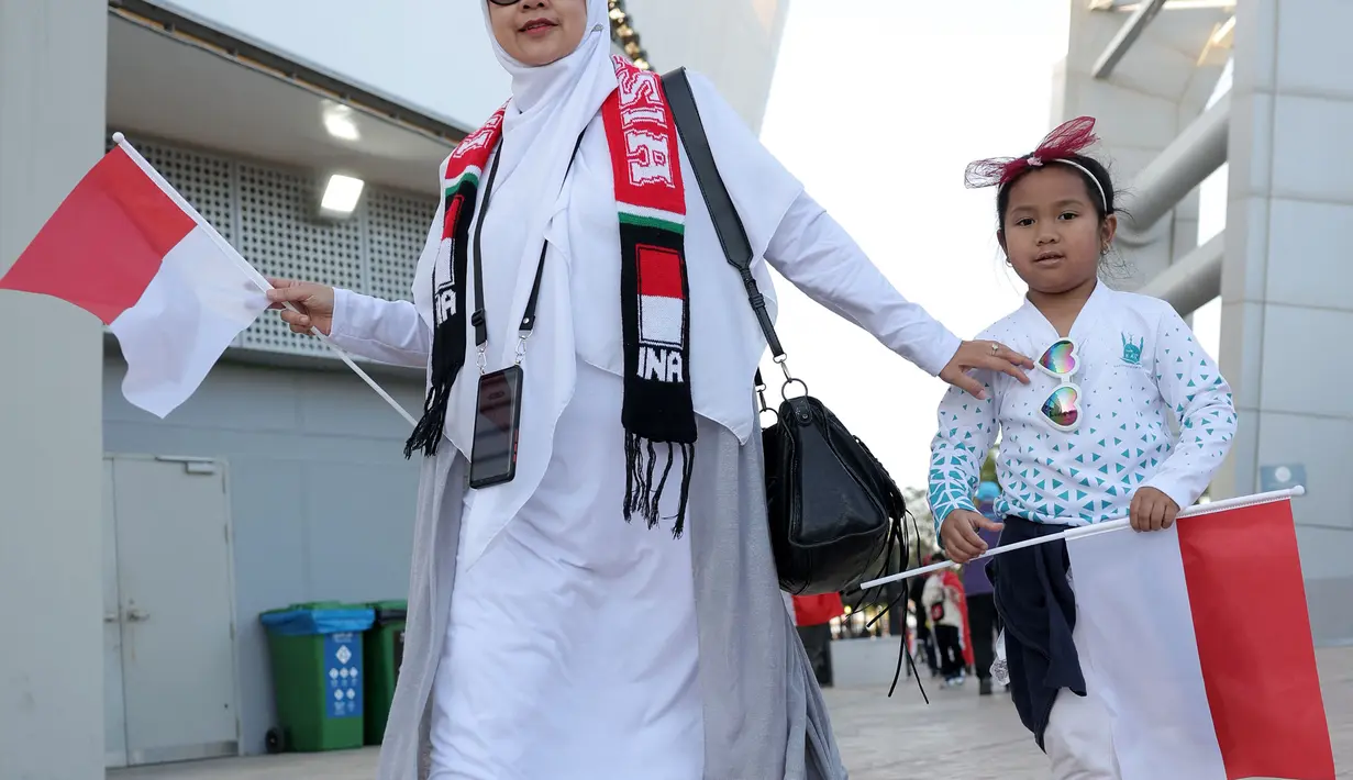 Seorang suporter wanita Indonesia bersama sang anak tiba di stadion sebelum dimulainya laga kedua Grup D Piala Asia 2023 antara Timnas Indonesia menghadapi Vietnam di Abdullah Bin Khalifa Stadium, Doha, Qatar, Jumat (19/1/2024). (AFP/Karim Jaafar)
