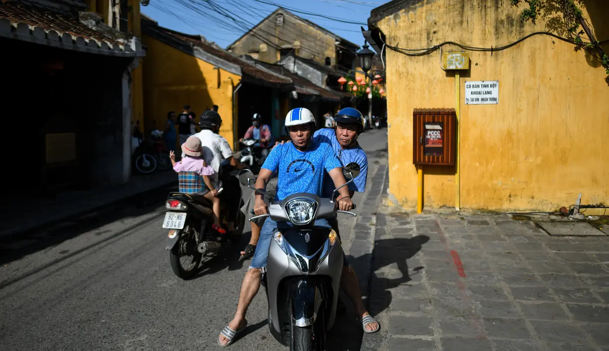Gambar pada 14 September 2019 menunjukkan pria Vietnam menaiki skuter di kota tua Hoi An. Kota Tua Hoi An merupakan destinasi wisata yang cukup populer di Vietnam, didukung oleh statusnya sebagai salah satu Unesco World Heritage Site. (Manan VATSYAYANA/AFP)