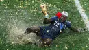 Pemain timnas Prancis, Benjamin Mendy memegang trofi Piala Dunia 2018 saat merayakan gelar juara setelah mengalahkan Kroasia pada  laga final di Luzhniki Stadium, Minggu (15/7). Prancis membekuk Kroasia dengan skor akhir 4-2. (AP Photo/Rebecca Blackwell)