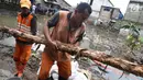 Pasukan oranye membawa kayu untuk memperbaiki tanggul yang jebol di kawasan Jatipadang, Jakarta Selatan, Selasa (12/12). Perbaikan tanggul sementara itu dilakukan dengan membuat tanggul pasir lalu menahannya dengan kayu. (Liputan6.com/Immanuel Antonius)
