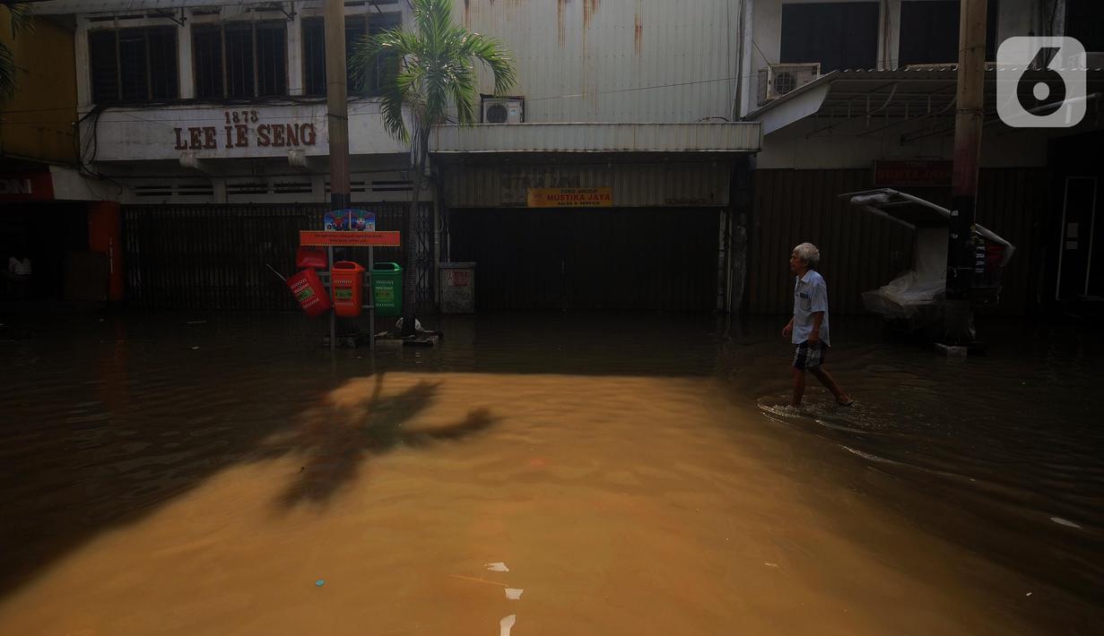 Warga melintas di depan pertokoan yang ada di kawasan Pasar Baru, Jakarta, Kamis (2/1/2020). Pasca banjir yang melanda sejumlah titik di Jakarta pada Rabu (1/1), aktivitas perniagaan di kawasan Pasar Baru masih terlihat sepi dan sebagian toko masih tutup. (Liputan6.com/Helmi Fithriansyah)