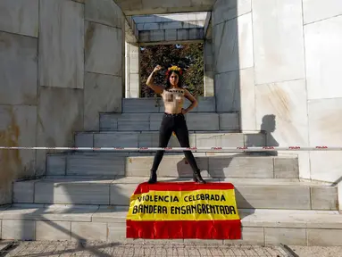 Aktivis perempuan Femen menuliskan "Illegitimate flag" di dadanya dan membawa bendera Spanyol bertuliskan 'Celebrated violence bloody flag' saat unjuk rasa di monumen Konstitusi Spanyol 1978 di Madrid, (11/10). (AFP Photo/Oscar Del Pozo)