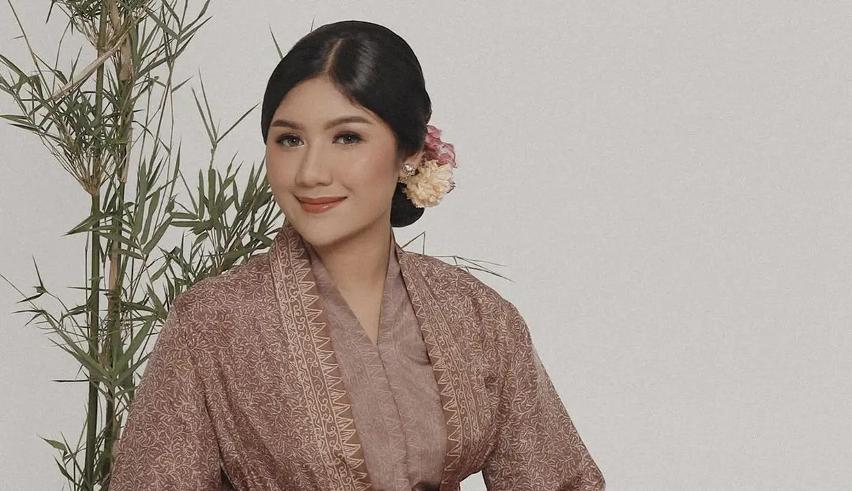 Outfit Erina memadukan kebaya berwarna cokelat dengan outer silk dan kain batik sebagai bawahan. Memperkuat siluet, Erina mengenakan belt berwarna emas. [@erinagudono]