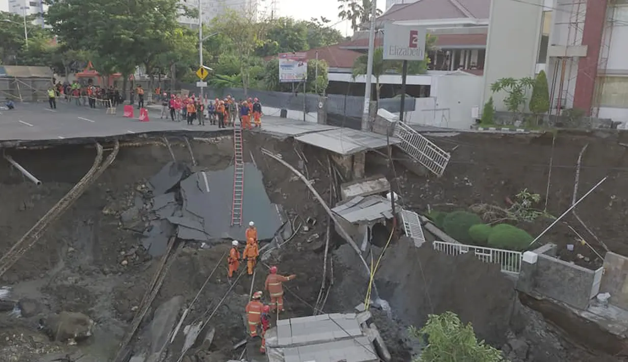 Petugas damkar memeriksa kondisi tanah amblas di Jalan Raya Gubeng, Surabaya, Rabu (19/12). Jalan raya yang amblas itu berlokasi di dekat sekitar RS Siloam atau dekat Kantor BNI Cabang Gubeng arah Jalan Sumatera (Liputan6.com/Pool/FB Dishub Kota Surabaya)