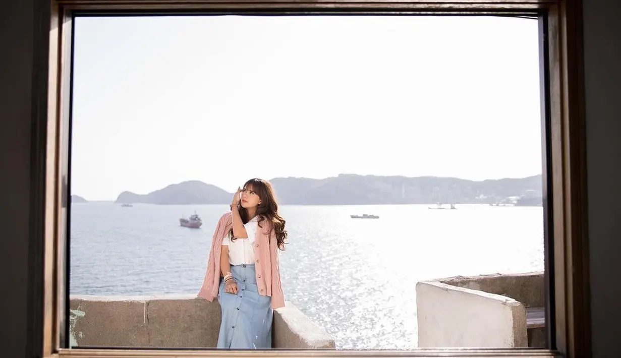 Berpose dengan pemandangan lautan, Audi Marissa tampil memadukan blouse, jaket, dan rok jeans yang stylish. (Instagram/audimarissa).