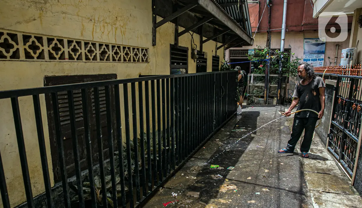 Warga membersihkan jalan usai terendam banjir di permukiman kawasan Kampung Melayu, Jakarta, Selasa (9/2/2021). Banjir yang berangsur surut dimanfaatkan warga untuk membersihkan rumah dan barang-barang dari endapan lumpur. (Liputan6.com/Faizal Fanani)