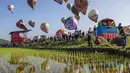 Festival juga bagian dari perayaan Syawalan untuk memeriahkan hari kemenangan. Tampak dalam foto, para pengunjung menyaksikan balon udara yang dihiasi motif tradisional sebelum diluncurkan selama festival tahunan yang diadakan untuk merayakan Hari Raya Idul Fitri, di desa Semayu, Wonosobo, Jawa Tengah pada Senin 23 Maret 2026. (DEVI RAHMAN/AFP)