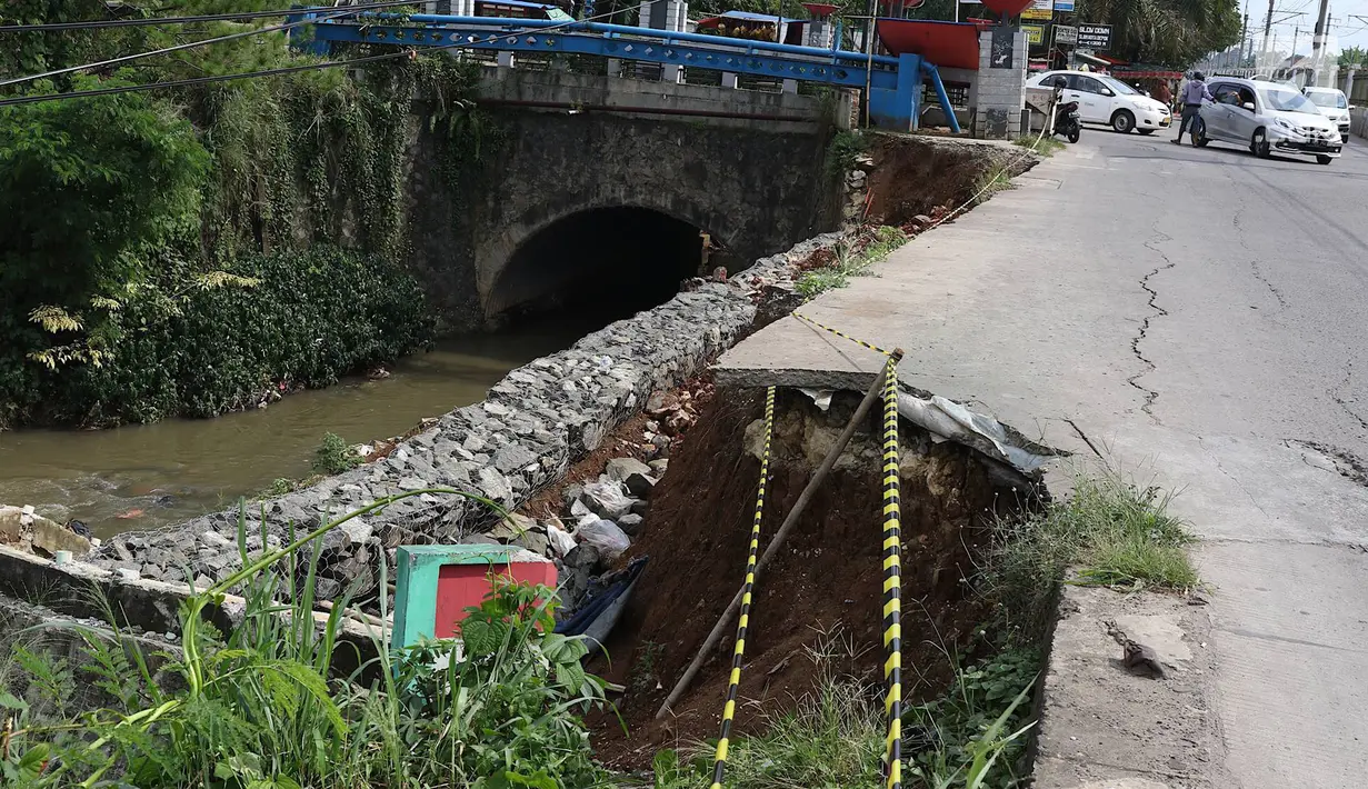 Kendaraan melintas di samping Jalan Raya Citayam yang amblas di kawasan Cipayung, Depok, Jawa Barat, Rabu (27/2). Kondisi tepi jalan yang tidak kunjung diperbaiki membahayakan pengguna jalan terutama saat malam hari. (Liputan6.com/Immanuel Antonius)