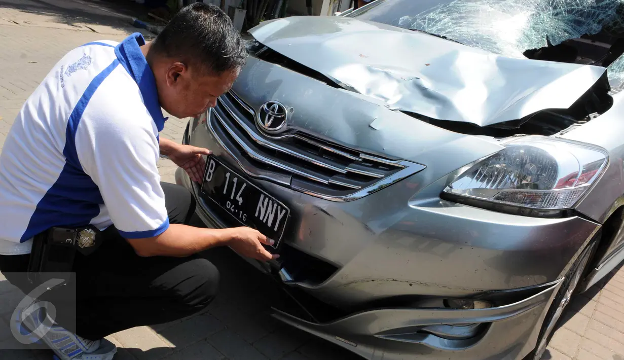 Petugas kepolisian menunjukkan plat mobil yang menabrak pejalan kaki di Jalan Boulevard Artha Gading, Jakarta, Sabtu (9/1/2016). Akibat kejadian tersebut, satu pengendara sepeda dan satu pejalan kaki meninggal di lokasi. (Liputan6.com/Helmi Afandi)