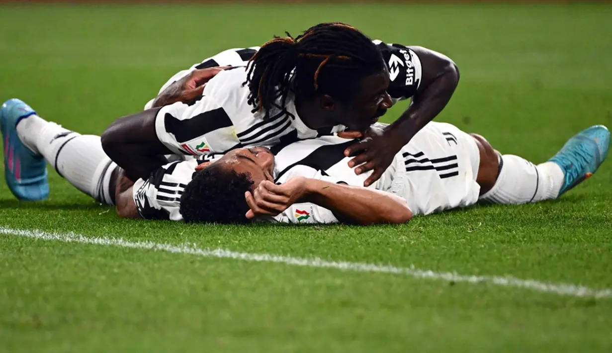 Pemain Juventus Danilo (bawah) merayakan dengan Moise Kean usai mencetak gol ke gawang Fiorentina pada pertandingan leg kedua semifinal Coppa Italia di Stadion Juventus, Turin, Italia, 20 April 2022. Juventus menang 2-0. (Marco BERTORELLO/AFP)