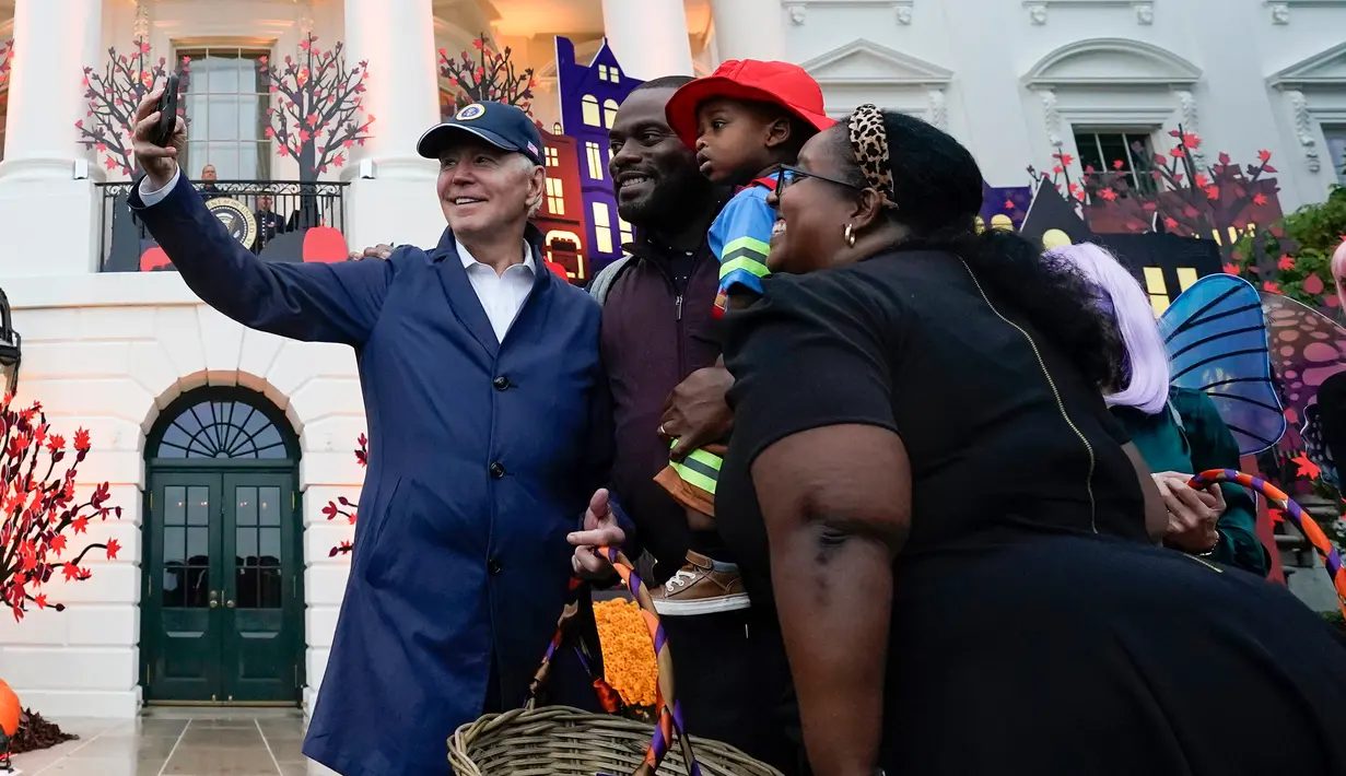 Presiden Amerika Serikat Joe Biden dan Ibu Negara Jill Biden berswafoto bersama keluarga saat mereka memberikan suguhan pada perayaan Halloween di South Lawn Gedung Putih, Washington, Amerika Serikat, 31 Oktober 2022. Halloween bertema "Trick-or-Treating in the President and First Lady's Neighborhood" itu tampak meriah dengan dekorasi rumah hantu di Gedung Putih. (AP Photo/Alex Brandon)