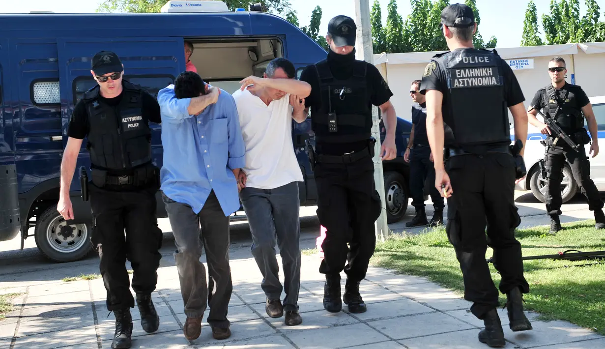 Polisi mengamankan dua dari 8 perwira militer pendukung kudeta Turki, di Alexandroupoli, utara Yunani, Minggu (17/7). 8 pria yang terbang dengan helikopter militer Turki itu ditahan petugas keamanan Yunani karena masuk secara ilegal (Sakis MITROLIDIS/AFP)