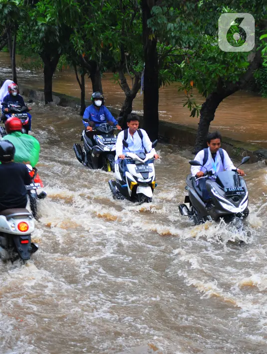 Sejumlah pengendara motor melintasi banjir di Jalan Benteng,  Duta Kranji, Kalibaru, Bekasi, Jawa Barat, Jumat (24/2/2023). Hujan yang turun di Bekasi sejak Kamis malam mengakibatkan sejumlah wilayah di Bekasi tergenang hingga lebih dari 50 cm. (merdeka.com/Imam Buhori)