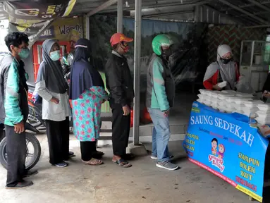 Relawan Yayasan Nasi Jumat (SiJum) Indonesia memberikan  makan siang di Warung Makan Gratis Beji, Depok, Jawa Barat, Rabu (9/3/2022). Makan siang gratis bagi masyarakat umum setiap harinya ini sudah berjalan sejak September 2021. (merdeka.com/Arie Basuki)