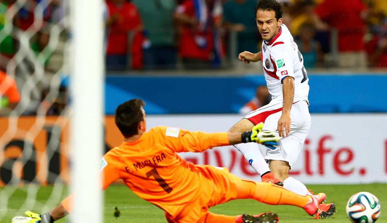 Pemain depan Kosta Rika, Marco Urena (kanan) berhasil mengecoh penjaga gawang Uruguay, Fernando Muslera, di babak penyisihan Piala Dunia 2014 Grup D di Estadio Castelo, Fortaleza, Brasil, (15/6/2014). (REUTERS/Dominic Ebenbichler)