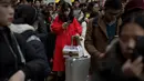 Seorang wanita bermain telepon genggam saat menungu keberangkatan kereta api di Beijing, China (23/1). Banyak dari mereka yang saat mudik membawa hadiah yang akan dibagikan pada orang tua dan kerabatnya. (AFP/Nicolas Asfouri)