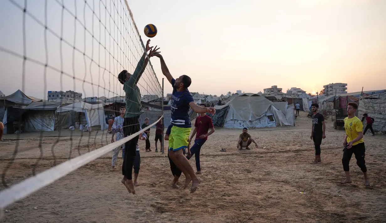 Anak-anak muda Palestina bermain voli di kamp tenda pengungsian di Zawayda, Jalur Gaza tengah, Selasa 4 November 2025. Diketahui, meski kesepakatan gencatan senjata antara Israel dan Hamas yang dimulai pada 10 Oktober 2025 masih berlaku, namun situasi kemanusiaan di Gaza masih memburuk. (AP Photo/Abdel Kareem Hana)