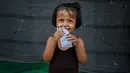 Seorang gadis pengungsi Rohingya tersenyum saat bermain di luar gubuknya di kamp pengungsi di New Delhi, India (12/9). Kekerasan yang dialami ratusan ribu warga Rohingya di Myanmar membuat mereka berlindung ke negara terdekat. (AP Photo/Altaf Qadri)