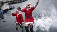Sejumlah peserta berkostum Sinterklas melompat ke dalam air dalam ajang Copa Nadal yang berlangsung di Barcelona's Port Vell, Barcelona, Kamis (25/12/2025) waktu setempat. Acara tersebut diikuti lebih dari 450 peserta. (AFP/Josep Lago)