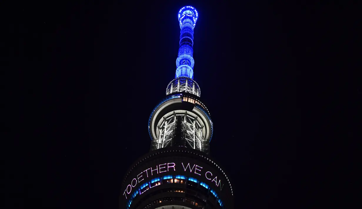 Menara Tokyo Skytree terlihat menyala dengan warna biru bertuliskan "Bersama Kita Semua Bisa Menang" di Tokyo, 5 April 2020. Ungkapan dukungan dan pesan harapan tersebut muncul di tengah merebaknya pandemi virus corona Covid-19. (CHARLY TRIBALLEAU/AFP)