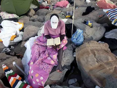 Seorang imigran membaca Al-Quran saat bulan suci ramadan di atas bebatuan laut Ventimiglia, perbatasan antara Italia-Prancis, (18/6/2015). Sekitar 200 imigran asal Eritrea dan Sudan berusaha memasuki perbatasan Italia. (REUTERS/Eric Gaillard)