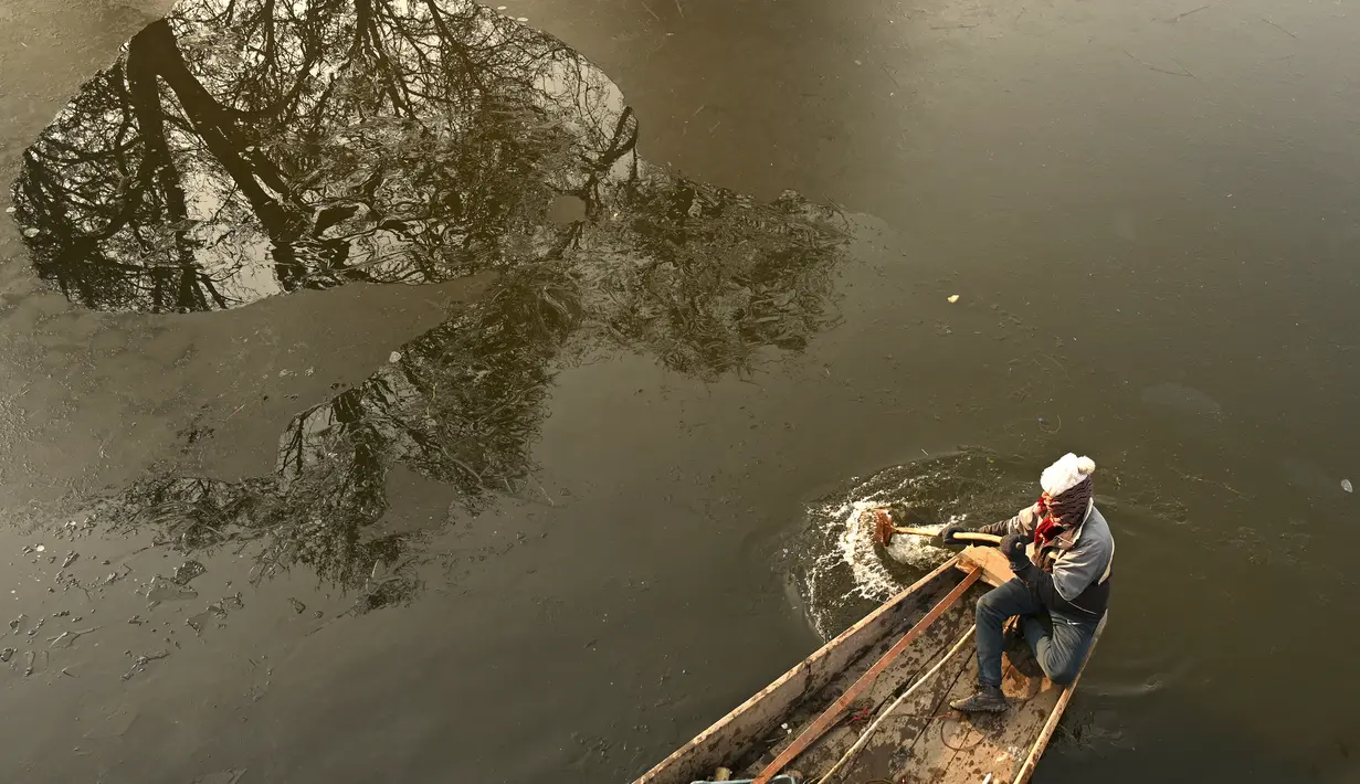 Tukang perahu menggunakan dayung memecahkan lapisan es di sepanjang bagian dalam Danau Dal pada pagi saat musim dingin di Srinagar (2/1/2023). Pada hari Senin Srinagar mencatat -5,4°C, Pahalgam -9,6°C dan Gulmarg -10°C sebagai suhu minimum. (AFP/Tauseef Mustafa)