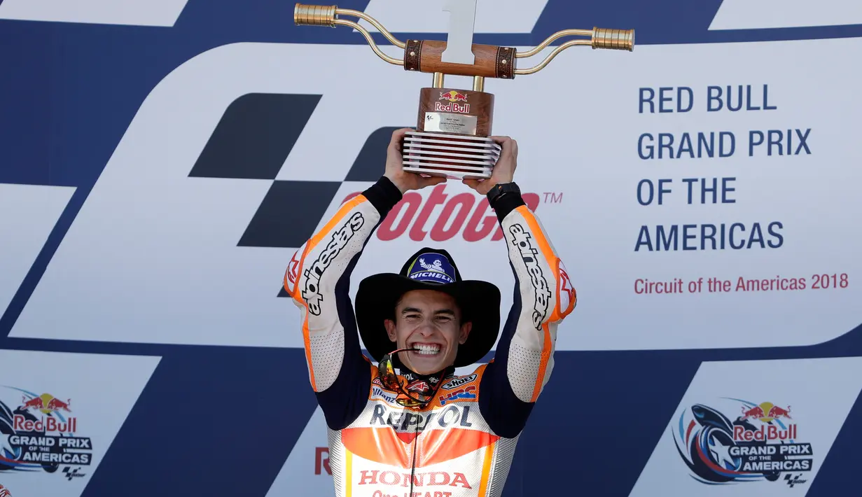 Pembalap Repsol Honda, Marc Marquez mengangkat trofi juara MotoGP Amerika di Circuit of the Americas (COTA), Austin, Minggu (22/4). Sebelum lomba, Marquez kena hukuman mundur tiga posisi karena melakukan pelanggaran di sesi kualifikasi. (AP/Eric Gay)