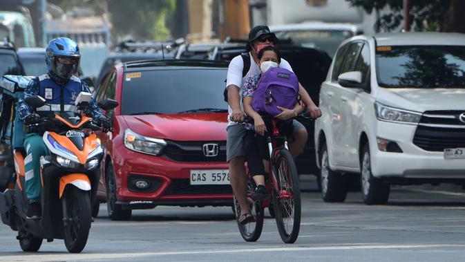 Sepasang warga menaiki sepeda di jalanan kota Manila pada 20 Mei 2020. Alat transportasi umum yang masih beroperasi dalam kapasitas terbatas membuat warga Filipina beralih ke sepeda saat berakhirnya masa karantina dan dimulainya periode The New Normal. (Ted ALJIBE/AFP)