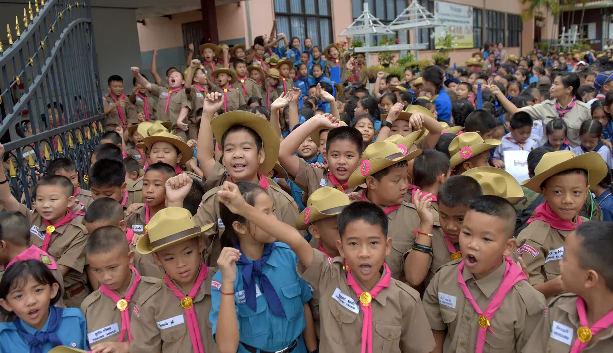 Para siswa bersorak-sorai di sebuah sekolah setelah tim sepak bola Thailand berhasil diselamatkan dari dalam gua di Chiang Rai, Thailand, Rabu (11/7). (AFP Photo/Tang Chhin Sothy)