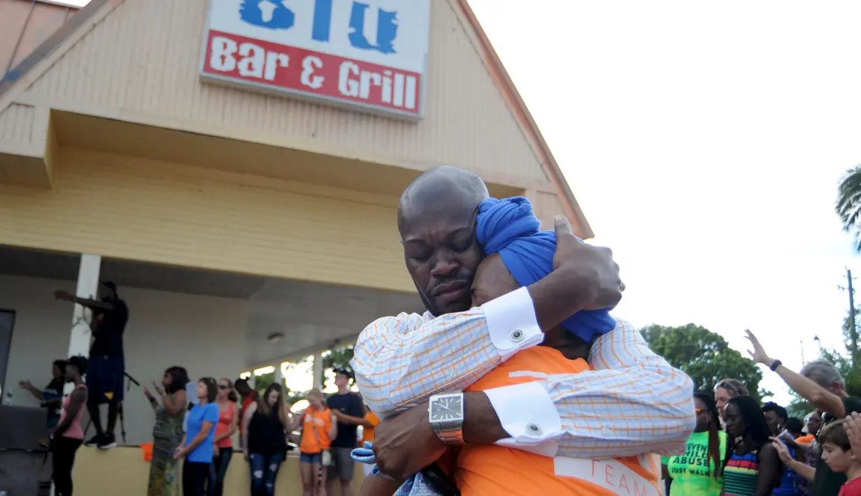 Dua orang kerabat saling berpelukan saat berdoa di lokasi penembakan di Club Blu di Fort Myers, Florida, Senin (25/7). Dua orang tewas dalam serangan penembakan di klub malam tersebut yang dilaporkan sebagai tempat pesta untuk remaja (REUTERS/Joe Skipper)