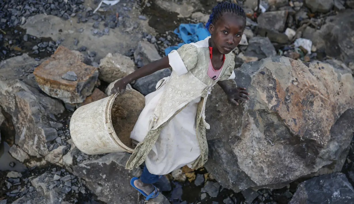 Irene Wanzila, 10, membawa seember batu pecah setelah ibunya yang kehilangan pekerjaan sebagai petugas kebersihan di sekolah swasta ketika pembatasan pandemi virus corona diberlakukan, di tambang Kayole di Nairobi, Kenya, 29 September 2020.  (AP Photo/Brian Inganga)