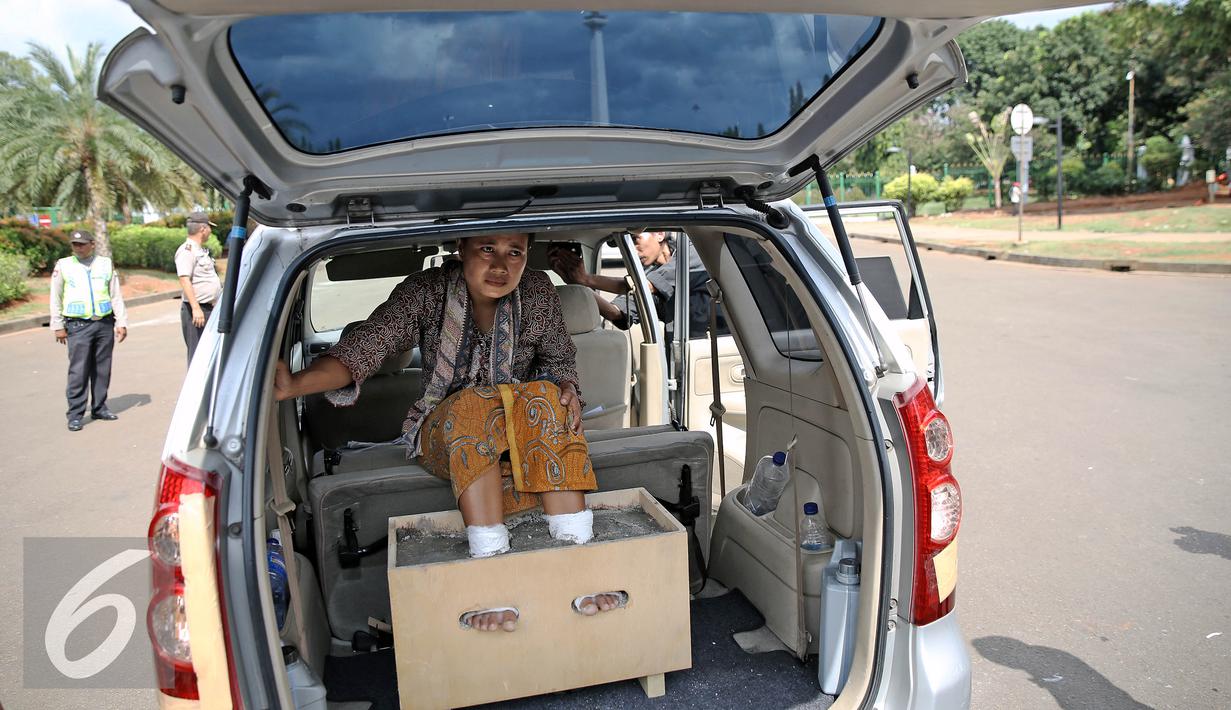 Petani perempuan yang disemen kakinya berada di dalam mobil saat mengelar aksi di depan Istana Negara, Jakarta, Selasa (13/4). Menurut mereka, pembangunan  pabrik semen tersebut dapat mengancam kehidupan petani dan masyarakat. (Liputan6.com/Faizal Fanani)