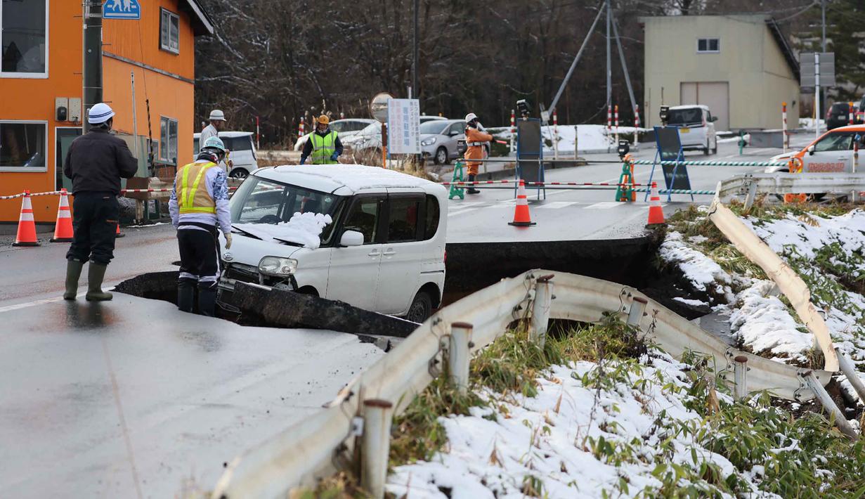 Gempa juga merusak jalan-jalan dan menyebabkan ribuan orang tanpa listrik dalam suhu udara dingin. Tampak dalam foto, sebuah kendaraan terlihat di jalan yang runtuh di kota Tohoku, Prefektur Aomori, Jepang, pada Selasa 9 Desember 2025. (JIJI Press/Japan OUT/AFP)