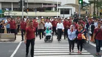 Presiden Jokowi dan Gubernur DKI Anies Baswedan yang memegang kursi roda ibundanya, Aliyah Rasyid menyeberang jalan menggunakan pelican crossing di Jalan Sudirman, Jakarta Pusat, Kamis (2/8/2018). (Liputan6.com/Hanz Jimenez Salim)