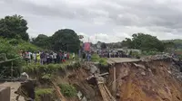 Warga melihat jalan ambruk oleh tanah longsor yang disebabkan hujan lebat melanda distrik Lemba, Kinshasa di Republik Demokratik Kongo pada Selasa (26/11/2019). Bencana tanah longsor ini juga telah melumpuhkan aktivitas warga dan lalu lintas. (AFP/Ange Kasongo)