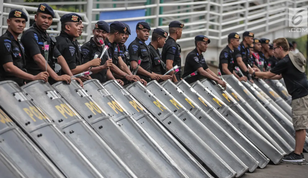 Petugas Brimob menerima bunga dari peserta aksi komunitas Spartan Nusantara di sekitar Gedung Bawaslu, Jakarta, Minggu (26/5/2019). Aksi tersebut sebagai bentuk terima kasih kepada TNI/Polri karena setia dan menjaga keamanan NKRI terkait sengketa pemilu. (Liputan6.com/Faizal Fanani)