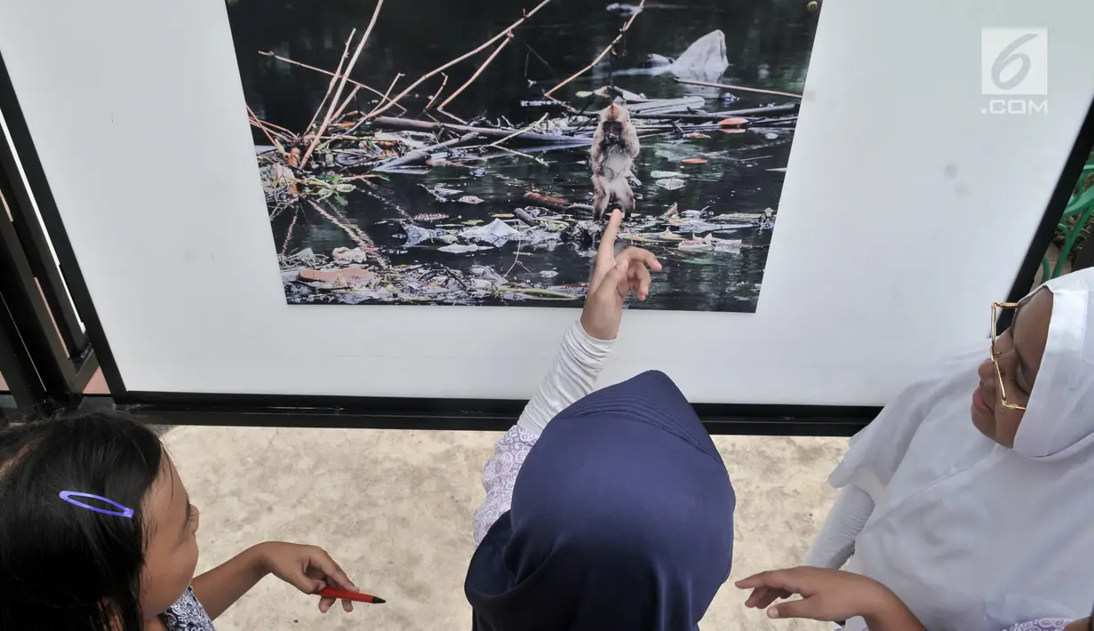 Siswa SD Negeri Menteng 01 mengamati karya foto yang dipamerkan dalam pameran fotografi Rekam Jakarta di Taman Menteng, Kamis (29/8/2019). Kegiatan tersebut dalam rangka edukasi bagi siswa mengenal profesi foto jurnalistik. (merdeka.com/Iqbal S Nugroho)