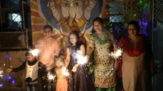 Sebuah keluarga India menyalakan petasan untuk merayakan Diwali, festival lampu Hindu, di Prayagraj, di negara bagian utara Uttar Pradesh, India, Senin (24/10/2022). Orang India di seluruh negeri merayakan Diwali, festival Hindu yang melambangkan kemenangan terang atas kegelapan. (AP Photo/Rajesh Kumar Singh)