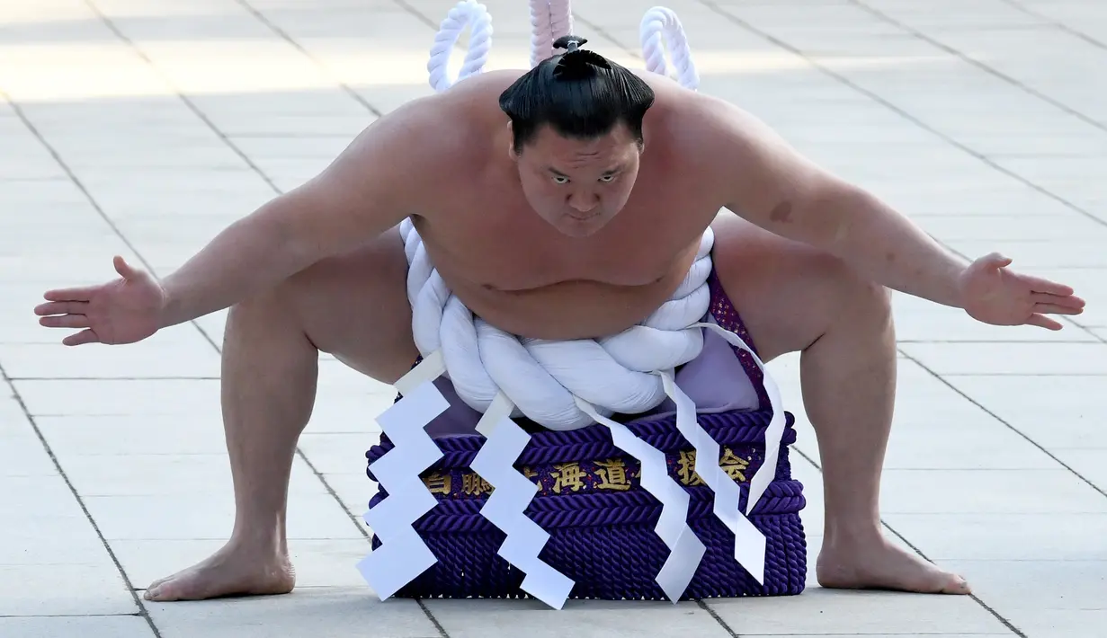 Juara Grand Sumo asal Mongolia, Hakuho melakukan upacara tradisional mengentakkan kaki untuk menyambut tahun baru di Kuil Shinto Meiji Shrine, Tokyo, Selasa (9/1).  Pesumo itu mengentakkan ke tanah dengan sekuat tenaga. (Toshifumi KITAMURA / AFP)