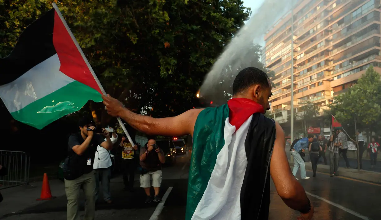 Seorang pria membentangkan bendera Palestina saat unjuk rasa memprotes kebijakan Presiden AS, Donald Trump soal Yerusalem sebagai ibu kota Israel di luar Kedubes AS di Santiago, Chile, (11/12). (AP Photo / Luis Hidalgo)
