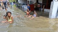 Anak-anak bermain dalam genangan. Banjir ini dipicu rob yang merendam rumah mereka di Kelurahan Pangeranan, Kabupaten Bangkalan.