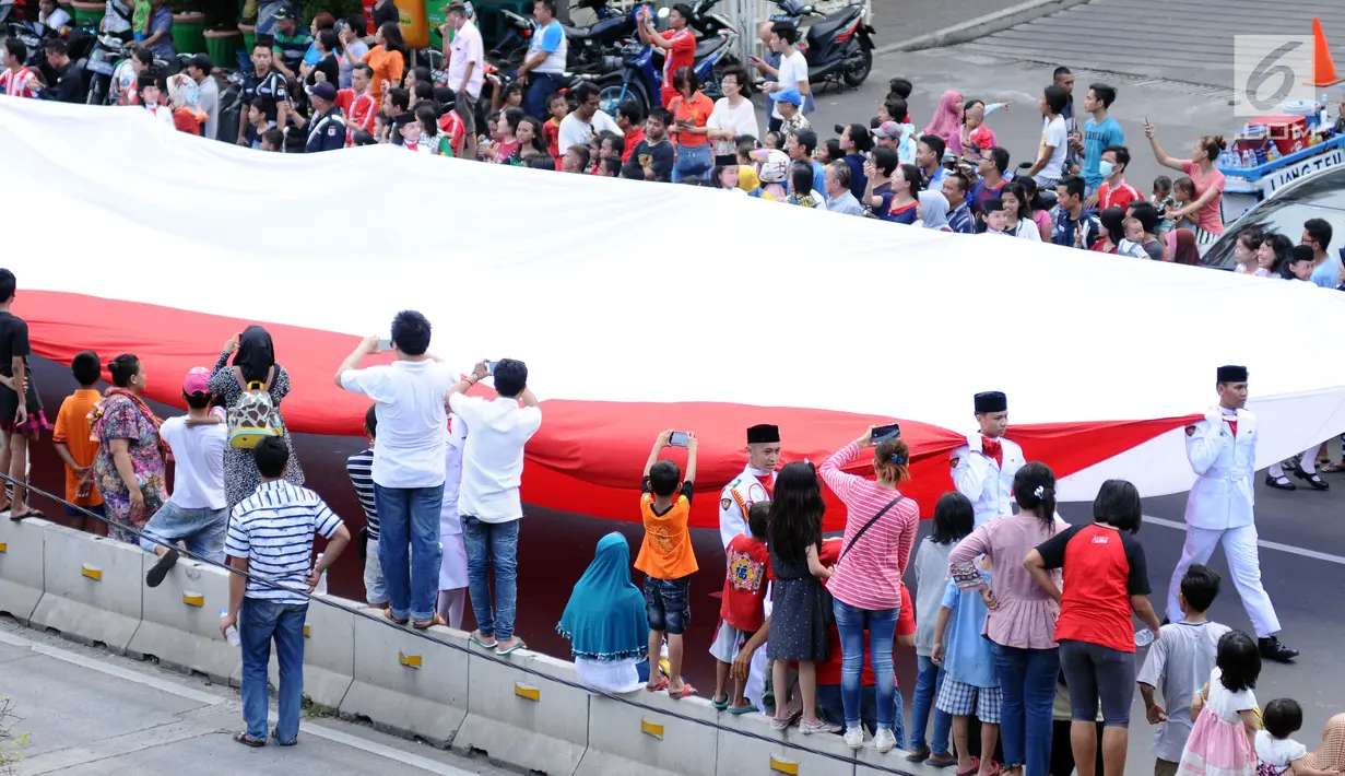 Warga menyaksikan iring-iringan bendera Merah Putih di ruas Jalan Gajah Mada, Jakarta saat karnaval Cap Go Meh 2018, Minggu (4/3). Beragam atraksi budaya ditampilkan pada karnaval Cap Go Meh 2018 di kawasan Glodok Jakarta.(Liputan6.com/Helmi Fithriansyah)