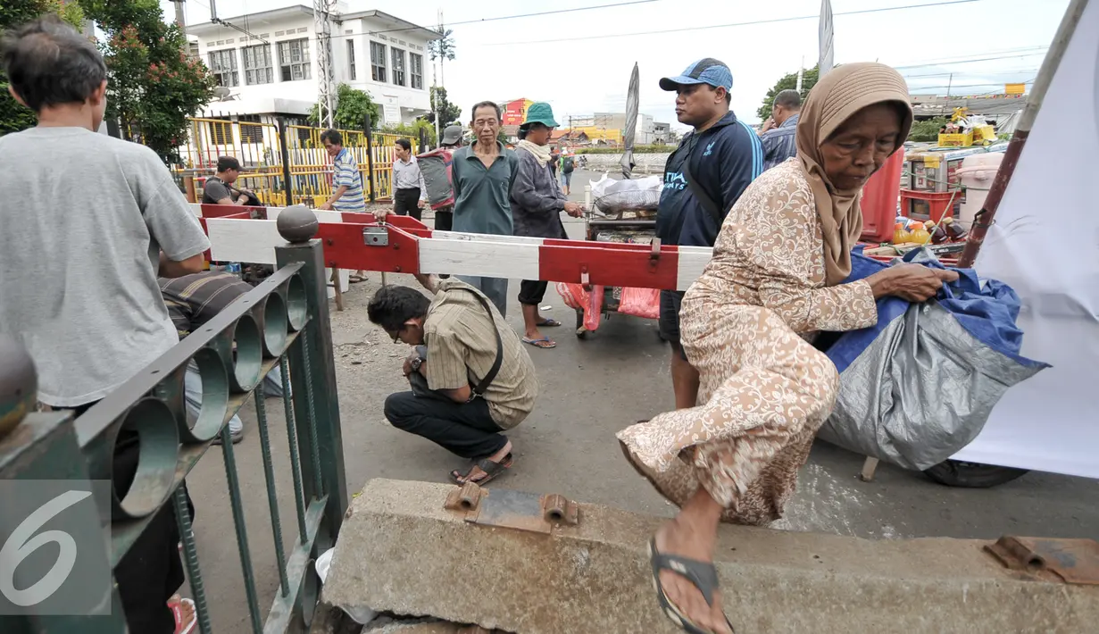 Warga melintasi palang pintu Kereta Api di perlintasan kereta Senen, Jakarta, Sabtu (1/10). Uji coba penutupan perlintasan kereta api Stasiun Pasar Senen mulai  diberlakukan 1 Oktober hingga 31 Oktober 2016. (Liputan6.com/Yoppy Renato)