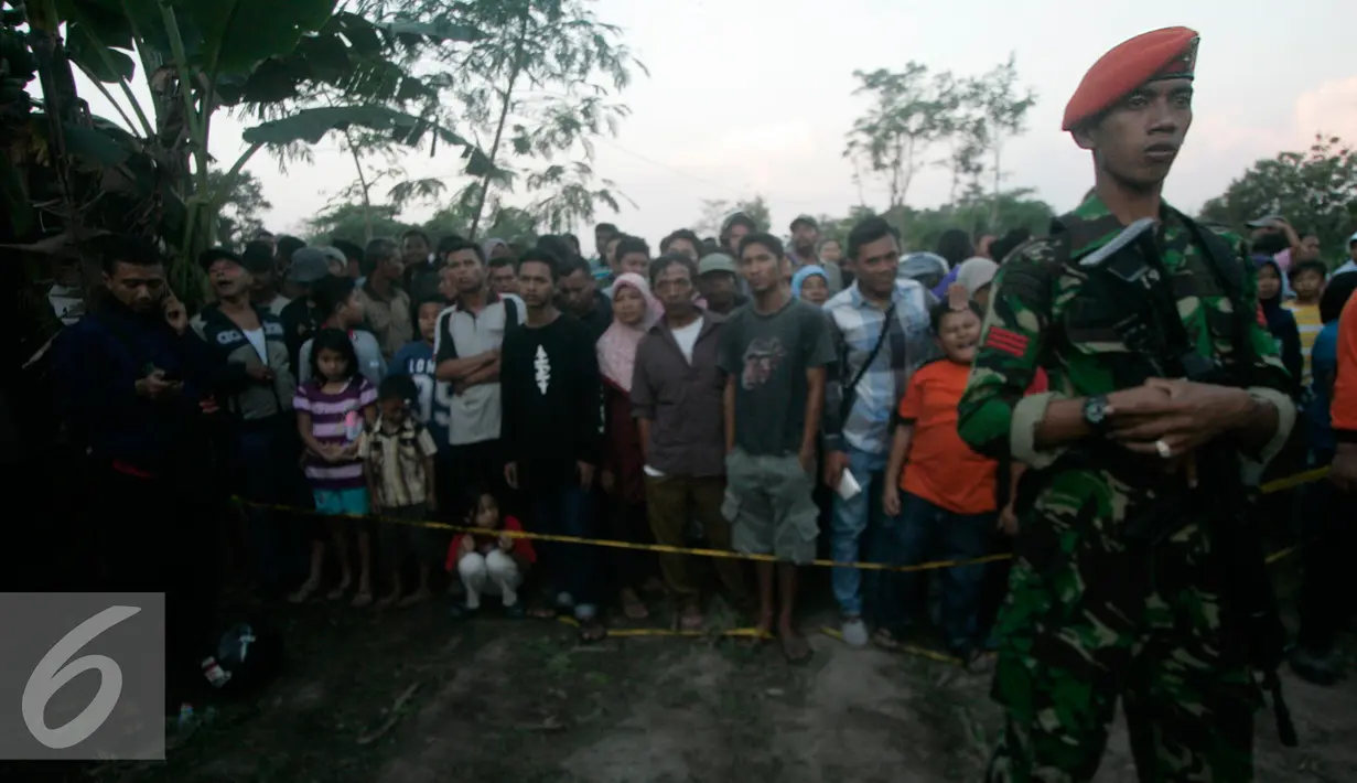 Petugas berjaga di sekitar lokasi helikopter jatuh yang sudah di tutup terpal di Dusun Kowang, Sleman (8/7). Heli jatuh setelah melakukan penerbangan dari Solo menuju Yogyakarta. (Liputan6.com/Boy Harjanto)