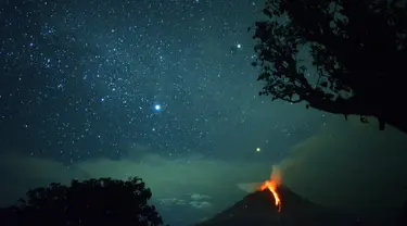 Pemandangan saat Gunung Sinabung memuntahkan lahar dan langit diterangi cahaya bintang di Karo, Sumatera Utara (28/12). Gunung Api Sinabung yang masih berstatus awas level empat kembali erupsi pada Rabu (27/12) sore. (AFP/Lana Priatna)