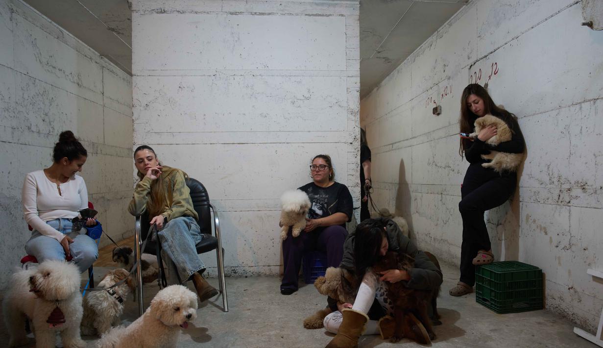 Serangan Iran juga menyebabkan kerusakan parah pada sejumlah bangunan tempat tinggal serta gangguan pada jaringan infrastruktur di beberapa wilayah di Israel. Tampak dalam foto, para pekerja salon anjing berlindung bersama anjing-anjing mereka di tempat perlindungan bom saat sirene serangan udara memperingatkan akan datangnya serangan rudal Iran di Ramat Gan, Israel, Rabu, 25 Maret 2026. (AP Photo/Oded Balilty)