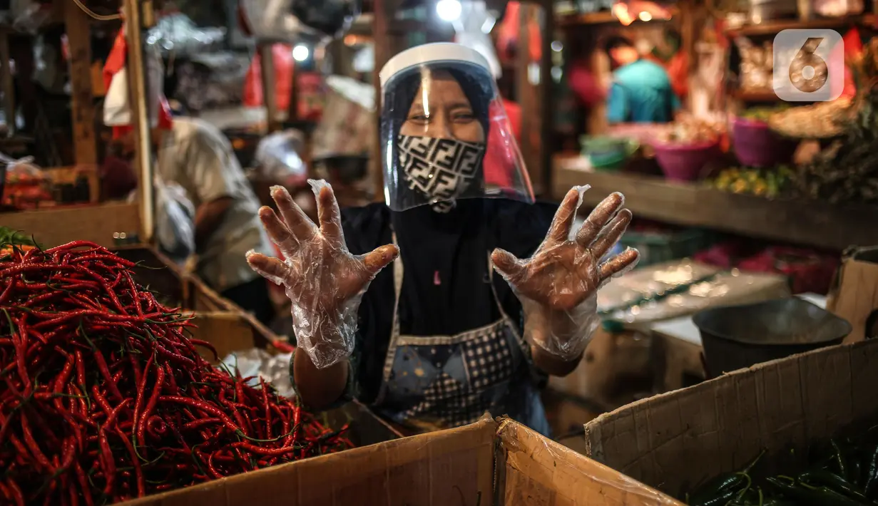 Salah satu pedagang menggunakan face shield dan sarung tangan saat melayani pembeli di Pasar Senen, Jakarta, Senin (1/6/2020). Saat era new normal, para pedagang di pasar rakyat diwajibkan menggunakan masker, face shield, dan sarung tangan selama beraktivitas. (Liputan6.com/Faizal Fanani)