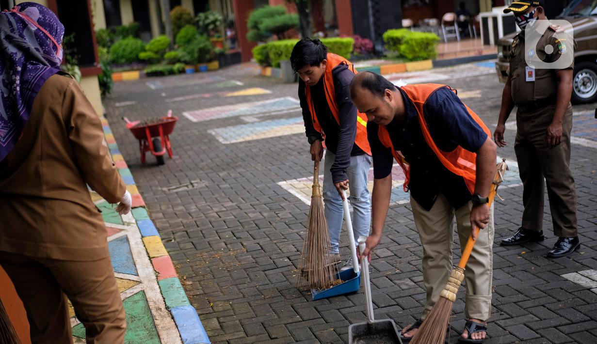 Sejumlah warga yang terjaring dalam razia penggunaan masker dihukum menyapu di Kelurahan Cimone, Kota Tangerang, Banten, Rabu (15/7/2020). Pemerintah Kota Tangerang memberlakukan sanksi sosial kepada pelanggar PSBB. (Liputan6.com/Angga Yuniar)