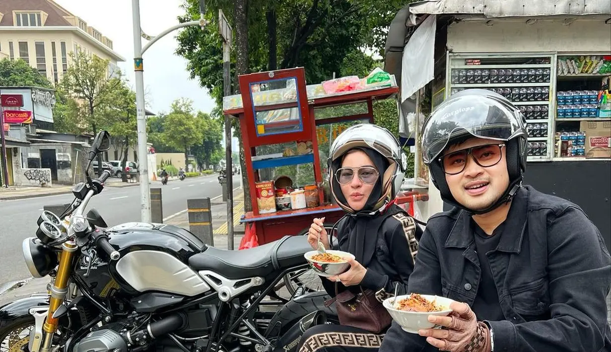 <p>Pasangan Shandy Purnamasari dan Gilang Juragan 99 terlihat santai saat makan bubur ayam kaki lima dengan outfit hitam. Di kepalanya masih menempel helm dan berkaca mata. (FOTO: instagram.com/shandypurnamasari/)</p>